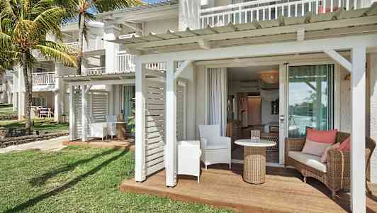 En uteplats med sittmöbler vid en vit byggnad och gräsmatta. (AI-genererad text)