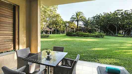 Uteplats med bord och stolar, utsikt mot en grönskande trädgård. (AI-genererad text)