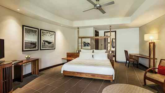 Modernt inrett hotellrum med dubbelsäng, skrivbord och stol, väggkonst och takfläkt. (AI-genererad text)