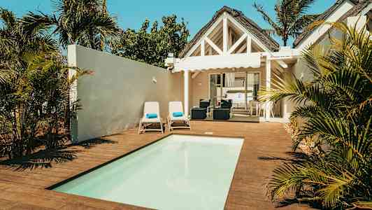 Villa med pool, solstolar och grön omgivning. (AI-genererad text)