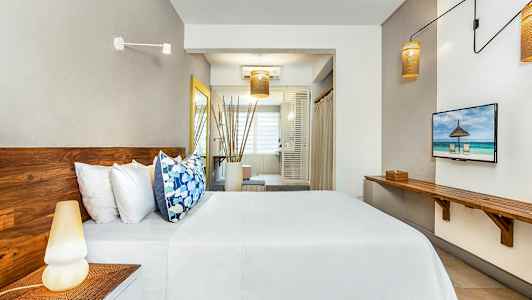 Bild av ett modernt hotellrum med trämöbler, säng med vita lakan och färgglada kuddar, och ett stort fönster i bakgrunden. (AI-genererad text)