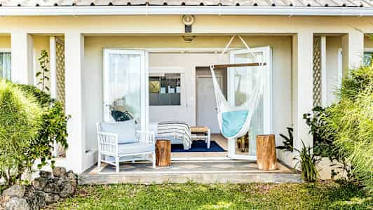 Bild av en terrass med öppen altandörr, en vit sittgrupp, en hängmatta och gröna växter runt omkring. (AI-genererad text)