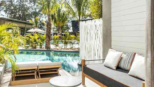 Utomhusområde med pool, solstolar och en soffa med kuddar. (AI-genererad text)