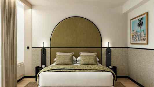 Ett hotellrum med en säng, gröna kuddar och en inramad tavla på väggen. (AI-genererad text)