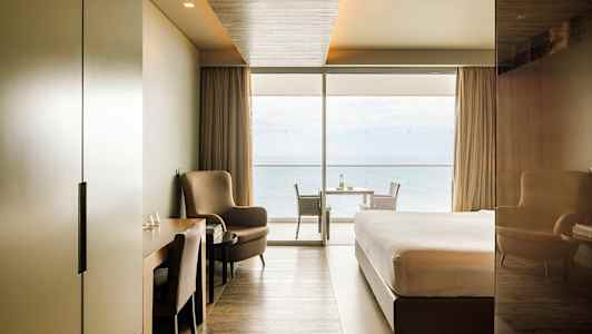 Modern hotellrum med havsutsikt genom stora fönster. (AI-genererad text)