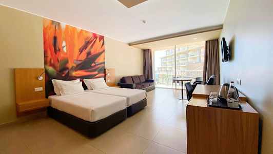 Hotellrum med två enkelsängar, soffa och balkong med utsikt. (AI-genererad text)