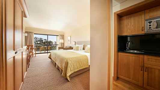 Bild av ett hotellrum med en säng och ett kök i trä. (AI-genererad text)