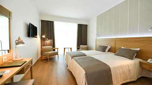 Hotelrum med två enkelsängar, skrivbord och sittplatser. (AI-genererad text)