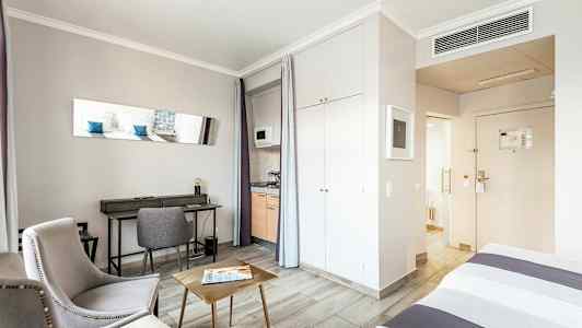 Rum med sittmöbler, skrivbord, säng och pentry. (AI-genererad text)