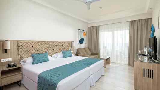 Bild av ett hotellrum med dubbelsäng, sittgrupp och balkong. (AI-genererad text)