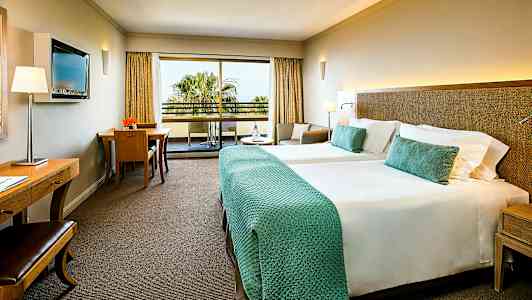 Hotellrum med två sängar och balkong. (AI-genererad text)