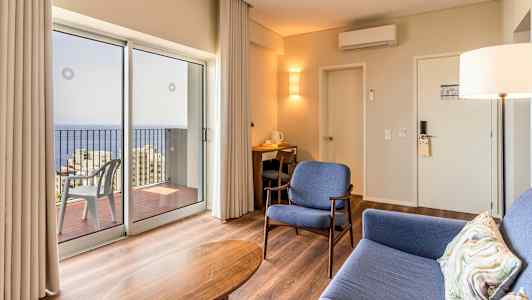 Modernt hotellrum med sittplatser och utsikt över havet genom stora fönster. (AI-genererad text)