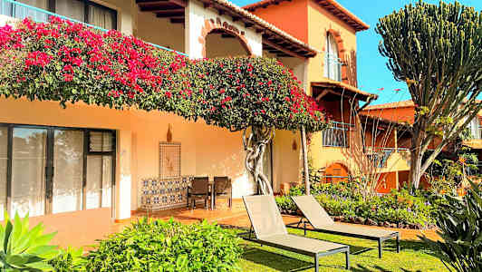 En byggnad med blomsterdekorationer, grönska och solstolar på en gräsmatta. (AI-genererad text)