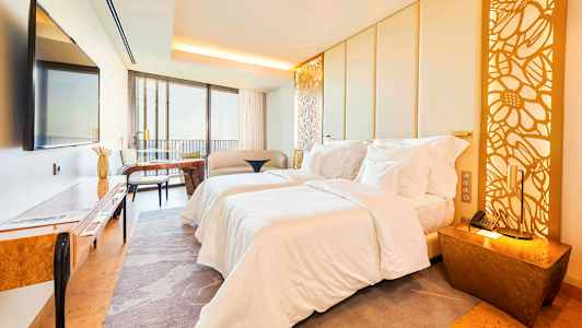 Bild på ett modernt hotellrum med två sängar, sittgrupp, möbler och dekorativ belysning. (AI-genererad text)