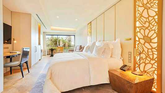 Ett modernt hotellrum med en stor säng, skrivbord, stol och balkong med utsikt. (AI-genererad text)