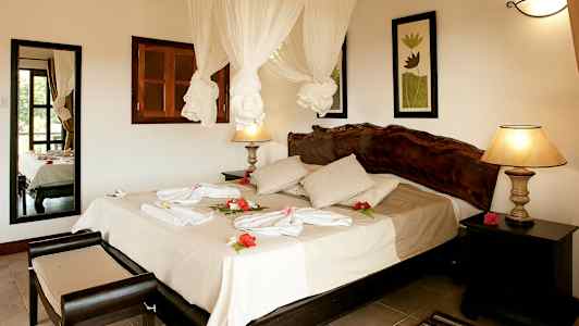 Hotellrum med dubbelsäng, dekorerat med blommor och handdukar. (AI-genererad text)