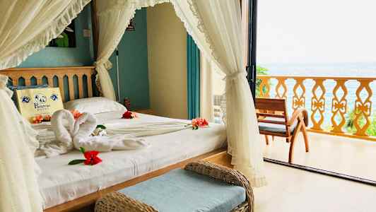 Ett sovrum med utsikt över havet, dekorerat med blommor på sängen. (AI-genererad text)