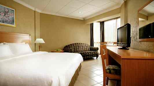 Hotellrum med stor säng, skrivbord, TV och soffa. (AI-genererad text)