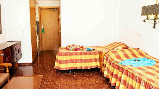 Ett hotellrum med två enkelsängar och en dörr till badrummet. (AI-genererad text)