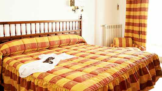 Ett hotellrum med en säng med gul och orange rutigt överkast. (AI-genererad text)