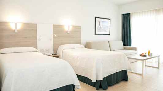 Ett hotellrum med två sängar, en soffa, ett bord och en frukostservering. (AI-genererad text)