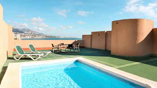 En terrass med pool, solstolar och utsikt över havet. (AI-genererad text)