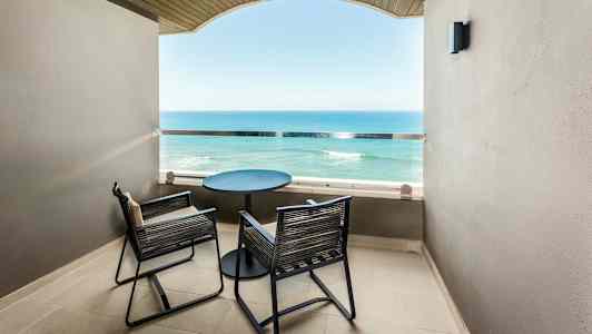 En balkong med två stolar och ett bord med utsikt över havet. (AI-genererad text)