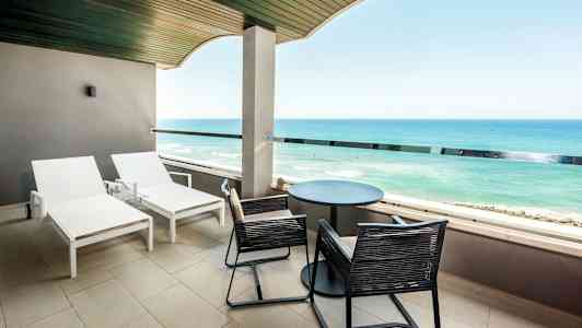 Balkong med solstolar och utsikt över havet. (AI-genererad text)