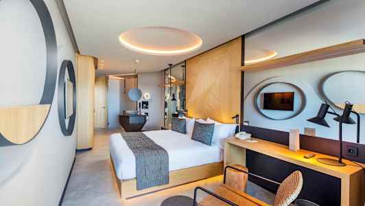 Moderna hotellrum med stor dubbelsäng, skrivbord och TV. (AI-genererad text)