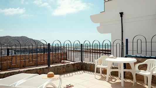 Terrass med solstolar, bord och stolar, havsutsikt. (AI-genererad text)