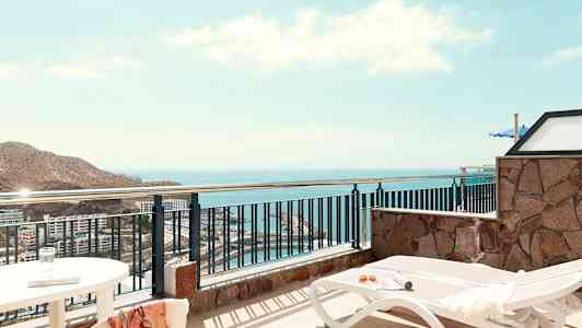 Utsikt från en terrass med solstolar och hav i bakgrunden. (AI-genererad text)