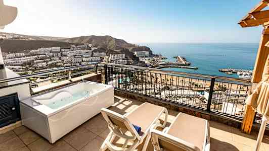 Balkong med två solstolar och en jacuzzi, utsikt över havet och omgivningen. (AI-genererad text)