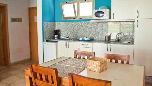 Ett kök med ett bord och fyra trästolar. (AI-genererad text)