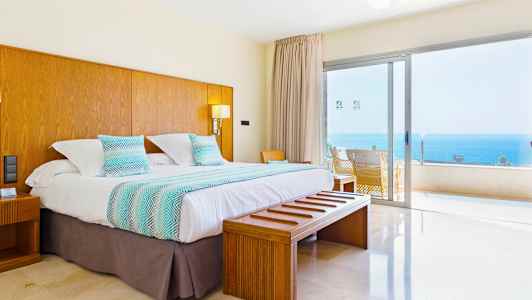 Dubbelrum med utsikt över havet genom en stor glaspanel. (AI-genererad text)