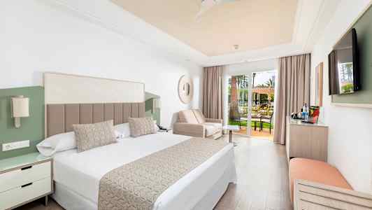 Ett hotellrum med dubbelsäng, soffa och glasdörrar till en terrass. (AI-genererad text)