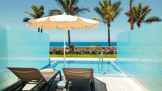 Bild av två solstolar och ett parasoll vid en privat pool med utsikt mot havet. (AI-genererad text)