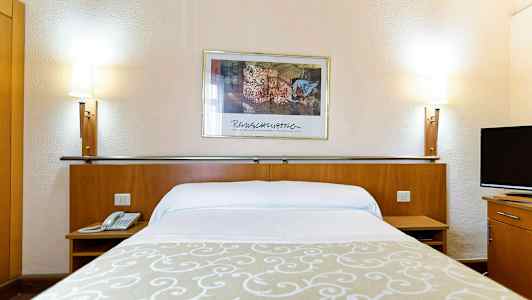 Hotellsäng med vita lakan, en beige dekoration, två sänglampor och en väggmålning i bakgrunden. (AI-genererad text)