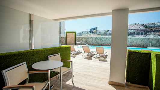 Utomhusterass med sittplats och utsikt mot simbassäng. (AI-genererad text)