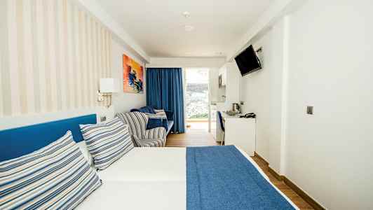 Ett hotellrum med en dubbelsäng med blå sängöverkast och randiga kuddar. (AI-genererad text)