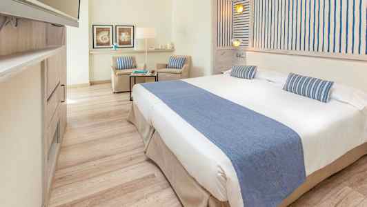 Ett ljust hotellrum med en bred säng och blåa dekorationer. (AI-genererad text)