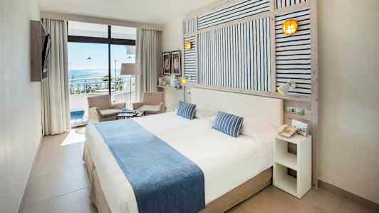 Dubbelrum med havsutsikt, möbler i ljusa färger. (AI-genererad text)