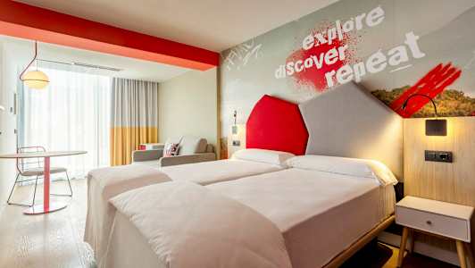 Ett modernt hotellrum med två enkelsängar och färgglada detaljer. (AI-genererad text)