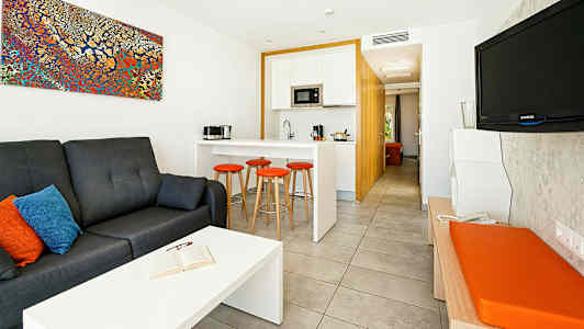 Ett modernt hotellrum med en sittgrupp, kök och TV. (AI-genererad text)