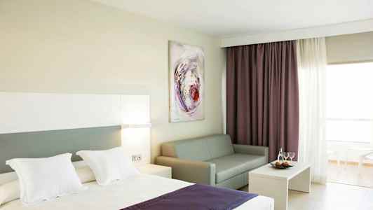 Hotellrum med säng, soffa, soffbord och gardiner. (AI-genererad text)