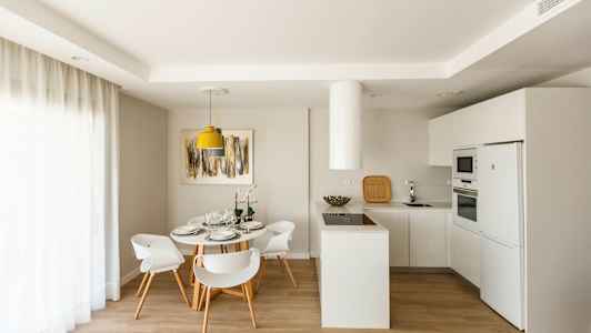 Modernt kök med matplats, vita möbler och ljus inredning. (AI-genererad text)