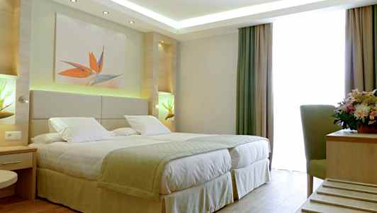 Hotellrum med en dubbelsäng, dekorationer och ett fönster med gardiner. (AI-genererad text)