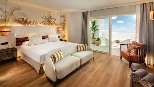 Ett hotellrum med en stor säng, en vit soffa och en balkong med möbler. (AI-genererad text)