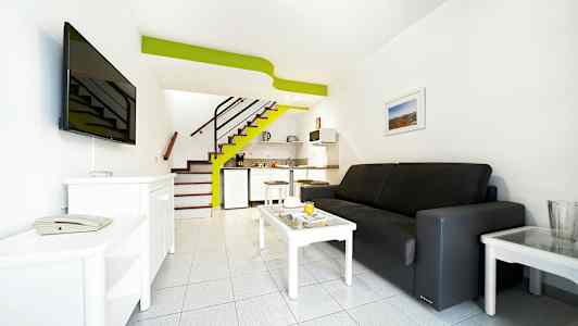 Ett hotellrum med soffa, soffbord, TV och liten köksdel. (AI-genererad text)