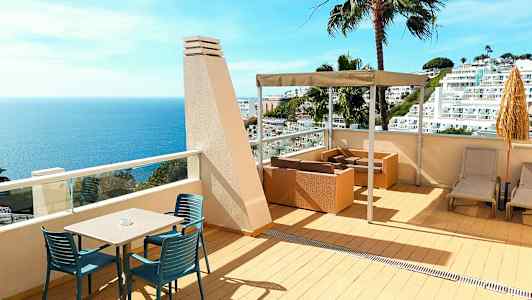 Terrass med havsutsikt, sittmöbler och solstolar. (AI-genererad text)