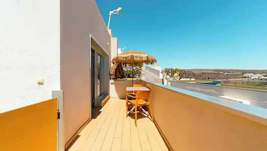 Balkongen med bord, stolar och parasoll med utsikt över omgivningen. (AI-genererad text)